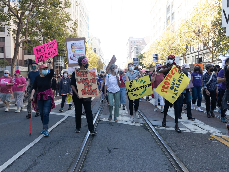 a group of people walking down a street holding signs