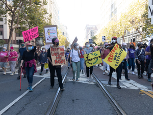 a group of people walking down a street holding signs