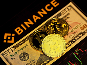 Three bitcoins on top of a $50 bill with the binance logo.