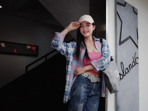 Woman in baseball cap and plaid shirt smiles.