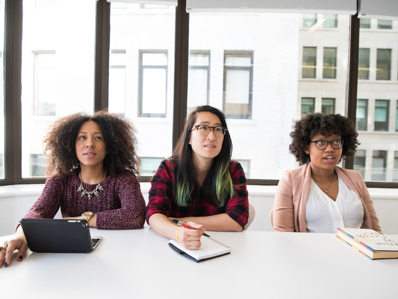 three women sitting at a table with a laptop