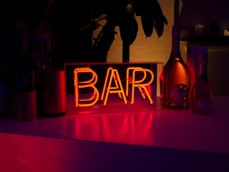 Bar neon sign surrounded with bottles