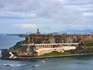 a large castle sitting on top of a lush green hillside next to the ocean
