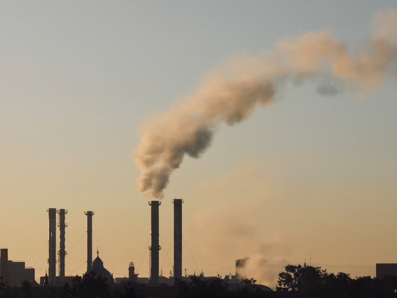a smokestack emits from a factory in the distance