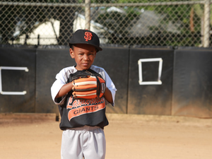 boy in orange and black jacket and white pants standing on field during daytime