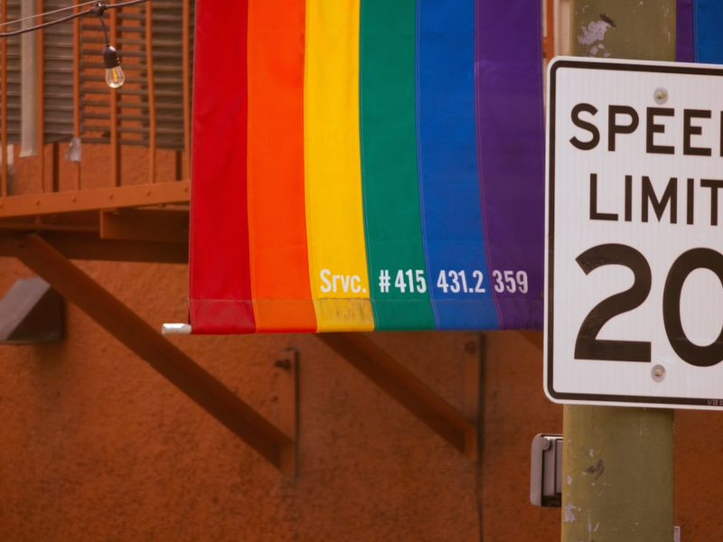 a speed limit sign next to a rainbow flag