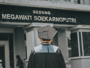 a man in a cap and gown walking towards a building