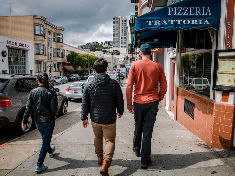 man in red long sleeve shirt and brown pants standing beside man in gray long sleeve