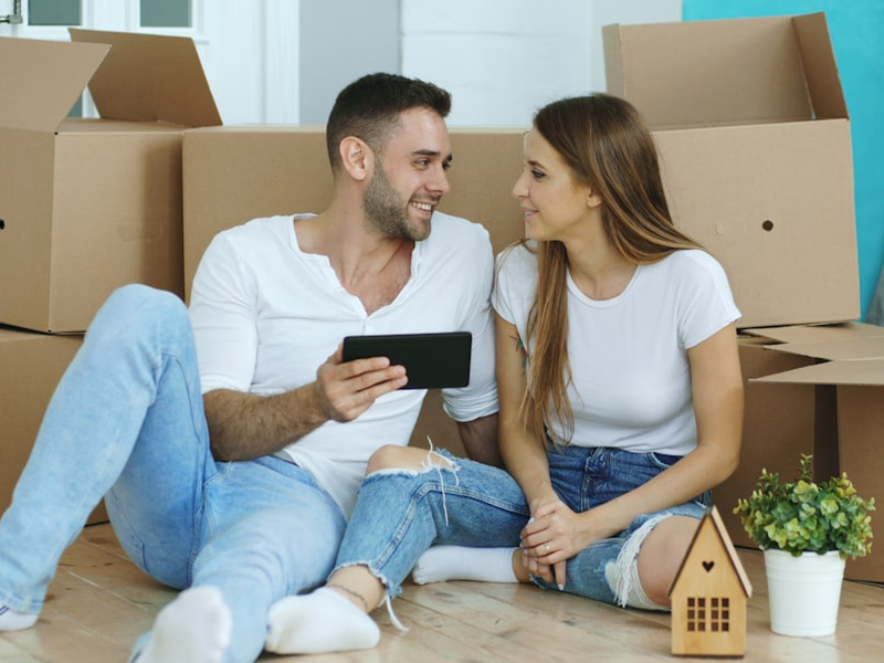 Young couple sitting on floor using tablet computer after reloction in their new house