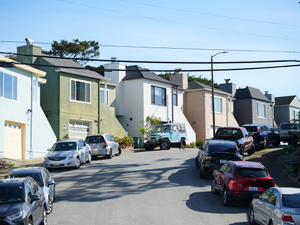 Cars parked on a residential street with houses.