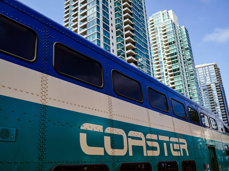 a blue and white bus parked in front of tall buildings