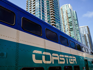 a blue and white bus parked in front of tall buildings