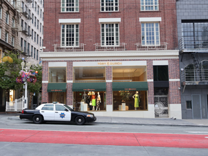 A police car parked outside the Tory Burch store at Union Square, San Francisco. The urban setting captures the bustling city atmosphere with pedestrians, high-end retail storefronts, and iconic city streets. Ideal for street photography, urban life, and cityscape enthusiasts.