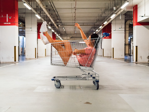 woman sitting in shopping cart at parking lot