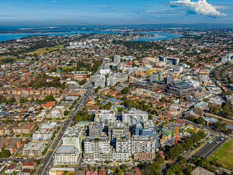 Aerial overview of Sydney metropolitan suburb with mixed-density housing, commercial infrastructure, and transport corridors, reflecting Australia’s evolving accommodation landscape and urban intensification.