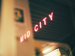 Neon sign reads mid city at night.