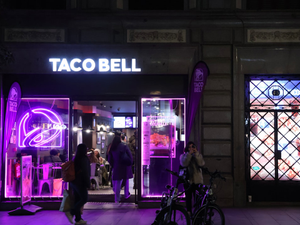 A purple lit store front with people walking by