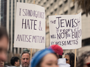 People hold up signs stating "I STAND AGAINST HATE & ANTISEMITISM" AND "THE JEWISH PEOPLE WILL NOT BE BULLIED BY ANTISEMITES" at the Unity Rally, a march against antisemitism in San Francisco.