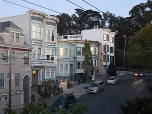 Row of colorful victorian houses on a street.