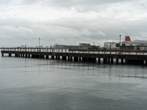 a pier on a cloudy day with a building in the background