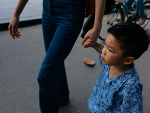 Child holding adult's hand walking on street