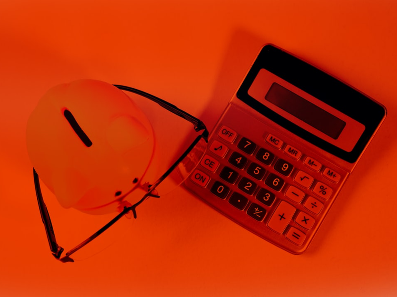 Calculator, helmet and glasses on a red background. Business concept.