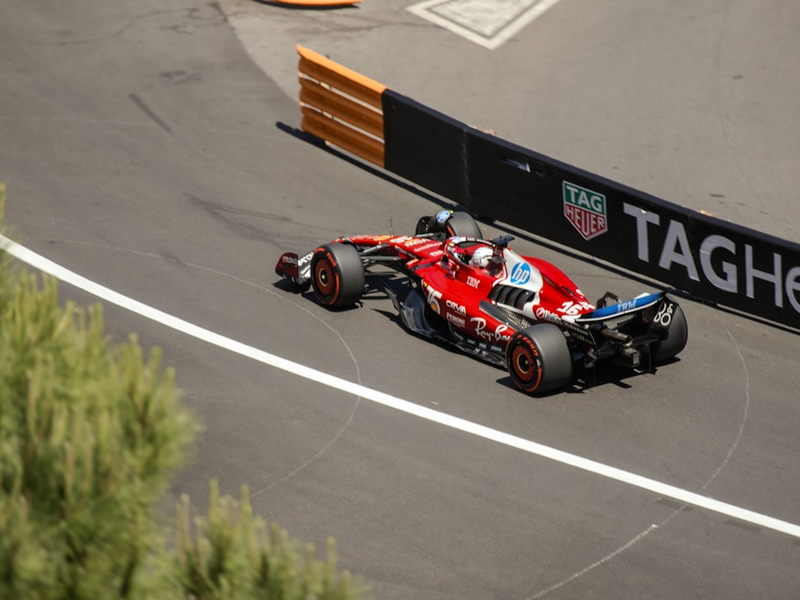 A Charles Leclerc's scarlet Ferrari blasts past the TAG Heuer barrier, clipping the apex of a sun‑soaked Monaco Grand Prix corner in 2025 street race.