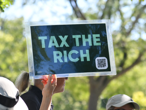 Person holds sign that says "tax the rich"