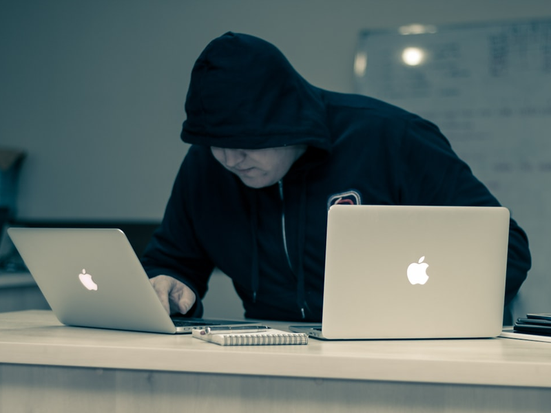 man in black hoodie using macbook