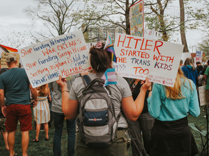 Protesters hold signs at a demonstration about transgender rights.