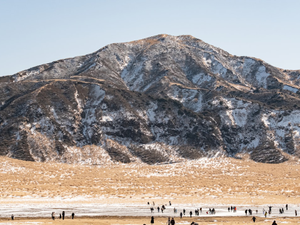 Snow-dusted mountain landscape with people below