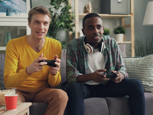 two men sitting on a couch playing video games