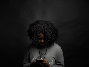 woman in gray long sleeve shirt holding black smartphone