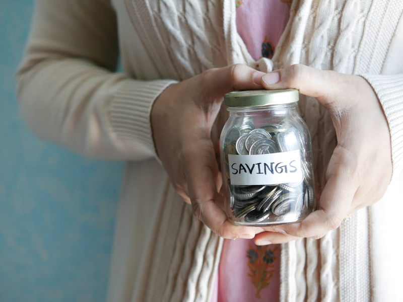 a woman holding a jar with savings written on it
