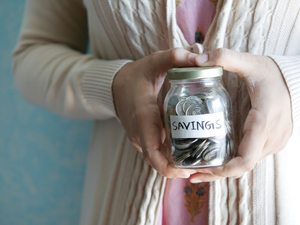 a woman holding a jar with savings written on it