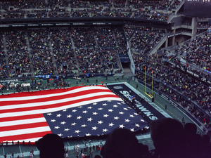 a large american flag is displayed in a stadium