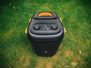 a black and yellow speaker sitting on top of a lush green field