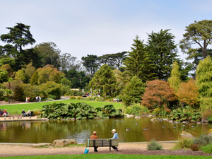 two people sitting on a bench near a pond