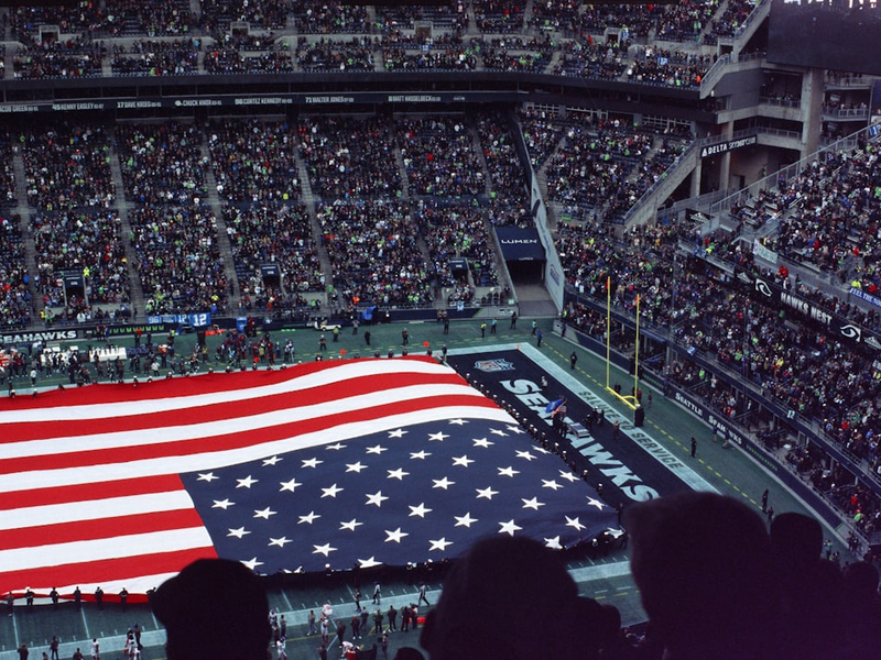 a large american flag is displayed in a stadium