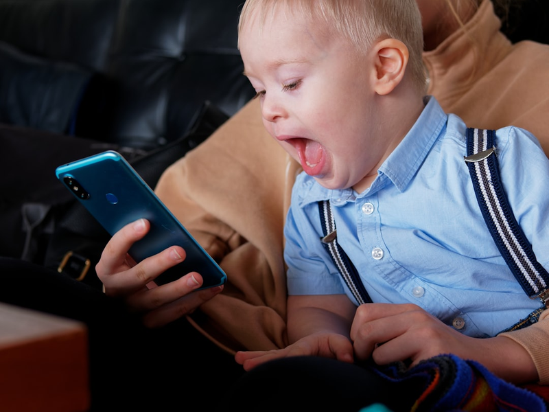 A young boy with Down syndrome is having fun on the phone with his sister.