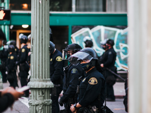 man in black police uniform standing near white concrete post during daytime