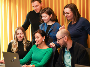 Colleagues in a meeting room looking at a laptop.