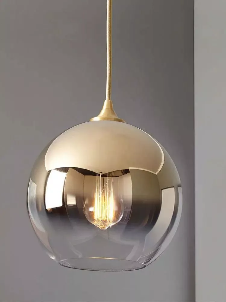 Sleek glass pendant light with a gold-accented top and visible filament bulb