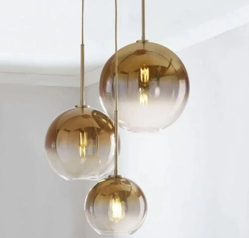 Sleek glass pendant light with a gold-accented top and visible filament bulb