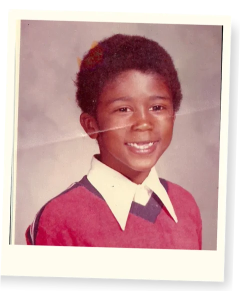 Childhood school portrait of Alex Jones smiling in a red sweater with a white collar