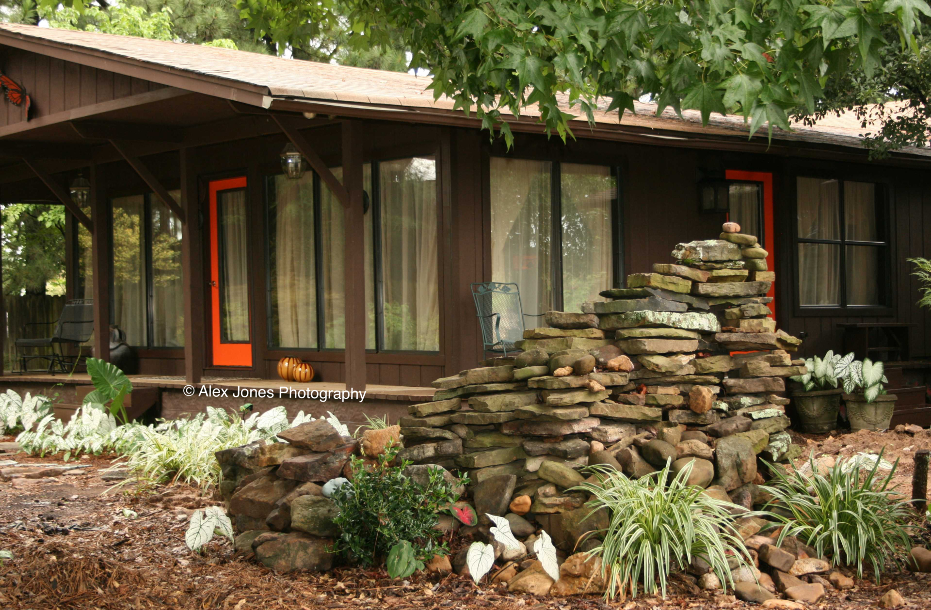 This photo shows a house with a beautiful rock garden and water feature made from stacked stones.