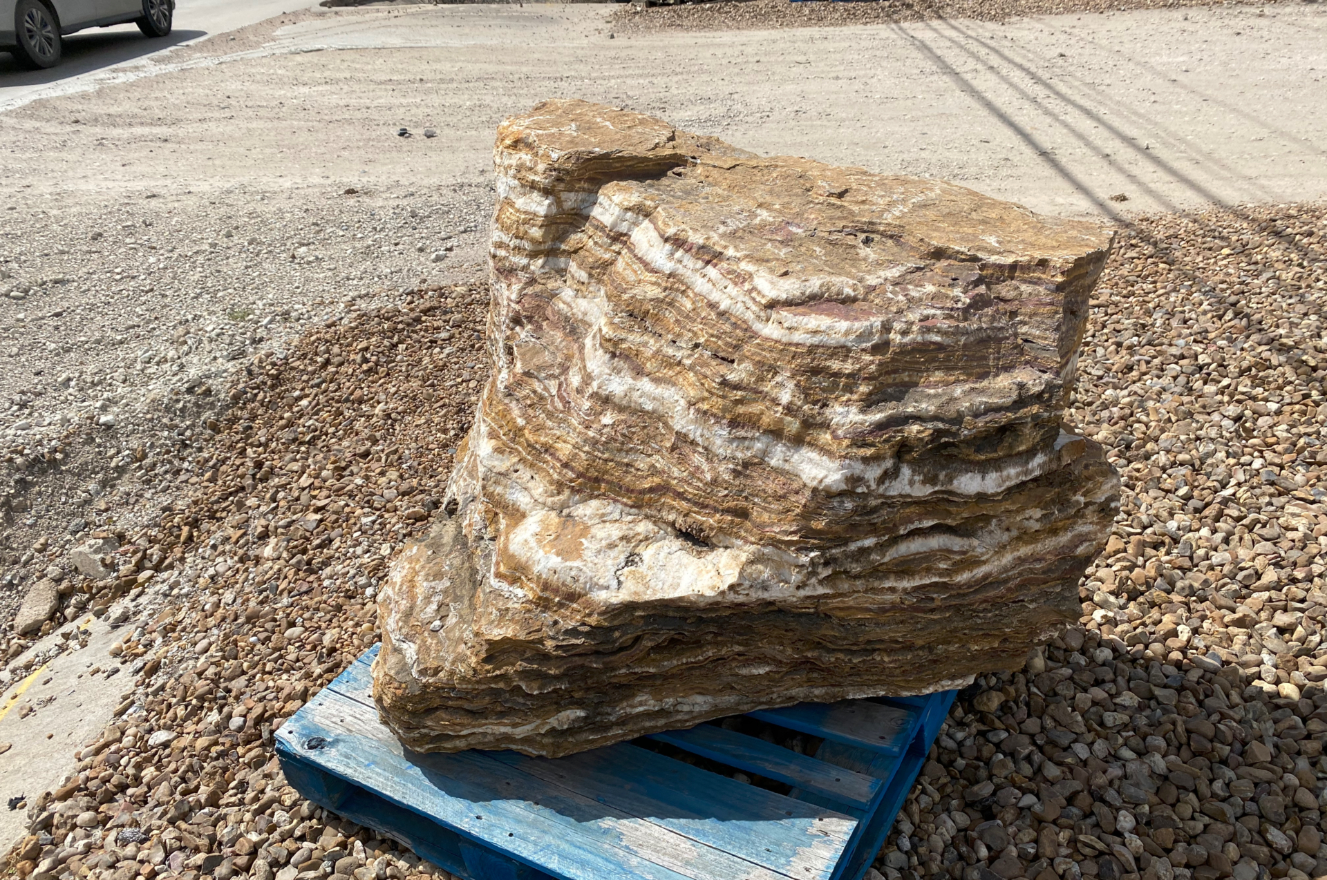 This photograph shows a layered rock formation displaying clear horizontal stripes of different colors—tan, brown, and white bands.
