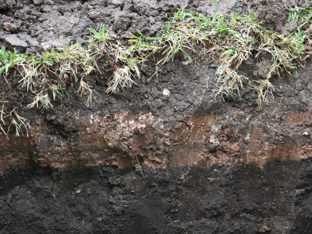 This image shows a cross-section of soil with three distinct layers stacked on top of each other.