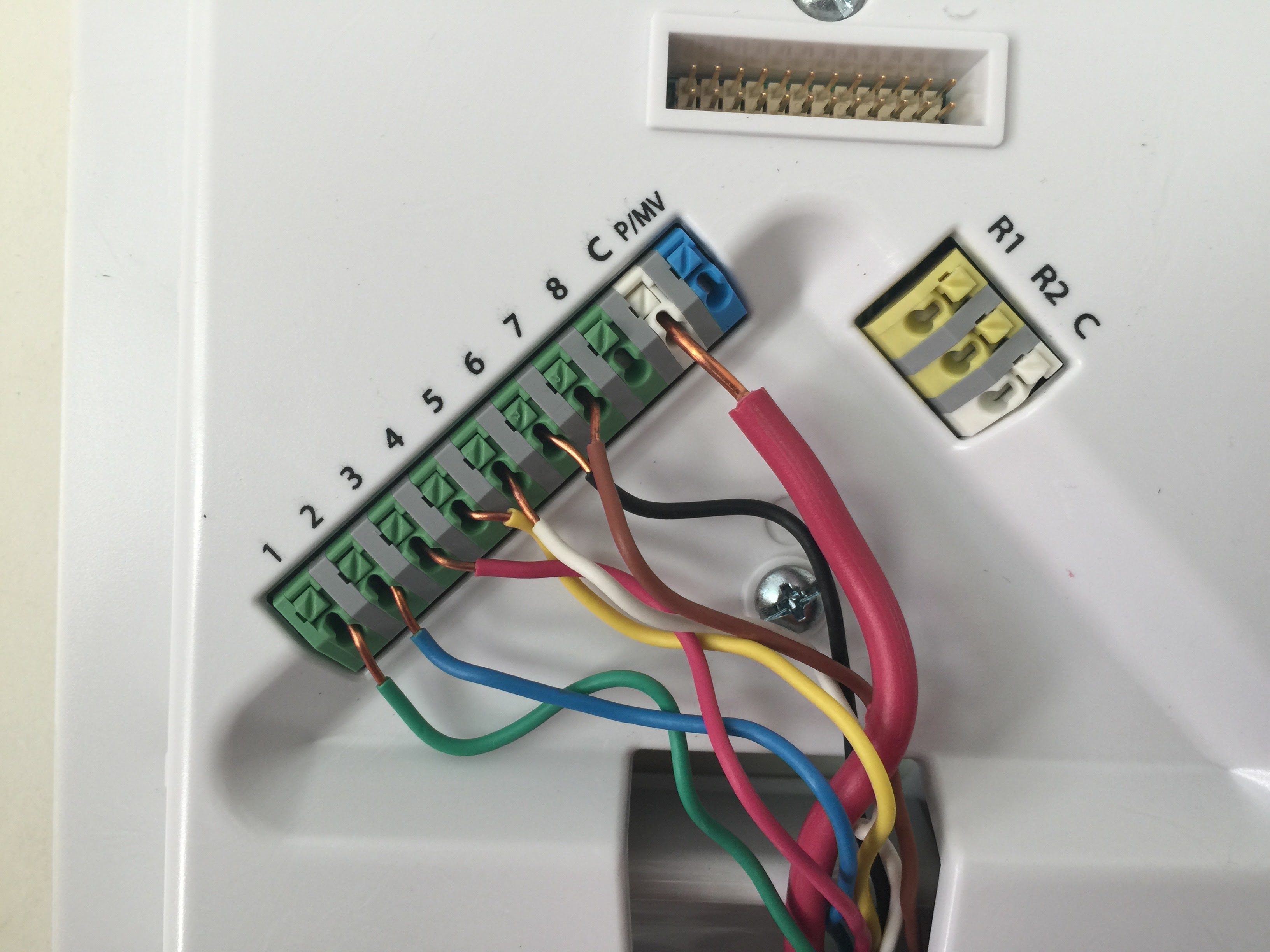 This image shows a circuit board with wires connected to different colored terminals (green, blue, yellow, pink, and black).
