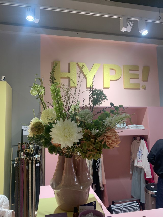 Een extra groot zijden bloemstuk in een roze sculpturale vaas voor een roze achtergrond met de tekst HYPE!